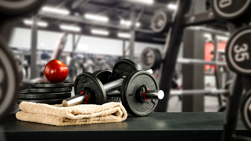 dumbbells weights and apple with gym background