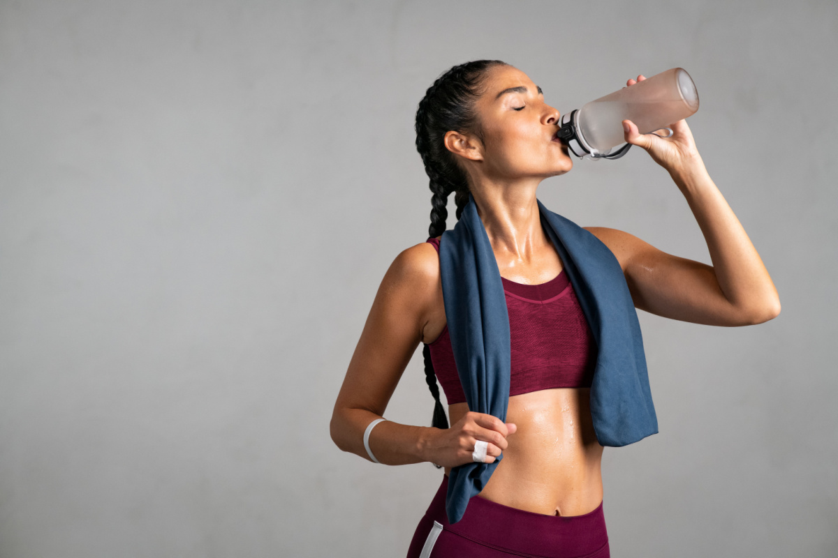 Young woman drinking water from a water bottle after an intense workout