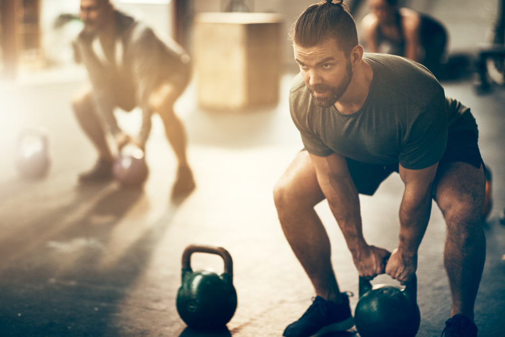 Group of men exercising with kettle bells, maintaining proper form
